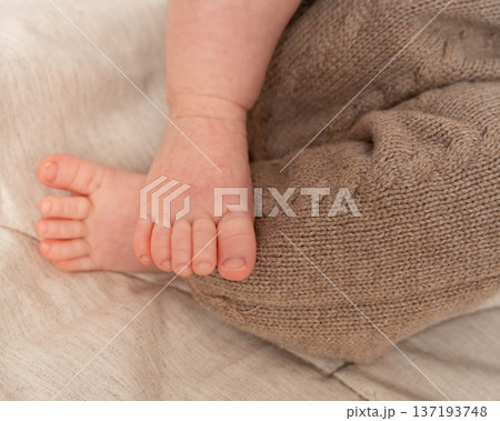 Horizontal close-up of a newborn babys foot resting on a cozy textured blanket. Warm tones, soft natural lighting, and neutral colors make this image perfect for parenting, baby care, and lifestyle Horizontal close-up of a newborn babys foot resting on a cozy textured blanket. Warm tones, soft natural lighting, and neutral colors make this image perfect for parenting, baby care, and lifestyle 137193748