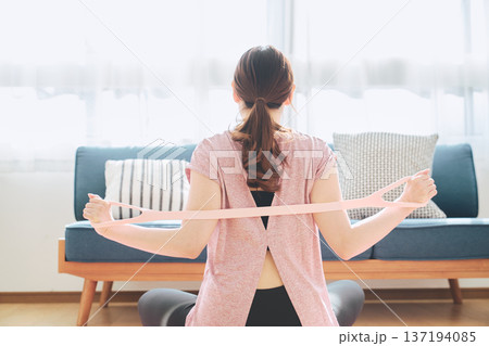 トレーニングチューブで背中のストレッチをする女性のホームフィットネス 137194085