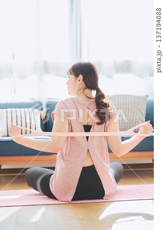トレーニングチューブで背中のストレッチをする女性のホームフィットネス 137194088