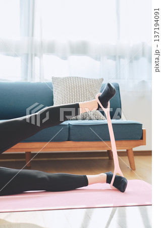ヨガマットの上でトレーニングチューブを使い下半身トレーニングをする女性 ヨガマットの上でトレーニングチューブを使い下半身トレーニングをする女性 137194091