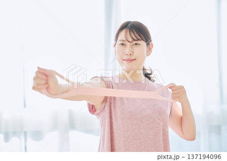 トレーニングチューブで腕のエクササイズをする健康志向の女性 137194096