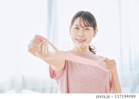 トレーニングチューブで腕のエクササイズをする健康志向の女性 137194099