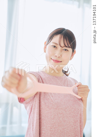 トレーニングチューブで腕のエクササイズをする健康志向の女性 トレーニングチューブで腕のエクササイズをする健康志向の女性 137194101