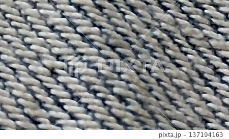 A close-up shot highlighting the intricate texture of woven fabric. The pattern blends light and dark shades, making it suitable for backgrounds, design elements, and creative projects. 137194163