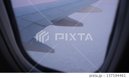 Airplane wing view above clouds during sunset with soft pastel colors Airplane wing view above clouds during sunset with soft pastel colors 137194461
