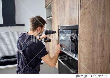 Technician Fixing Microwave Oven in Kitchen Cabinet 137195457