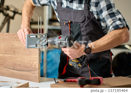 Carpenter drilling hole in wooden board 137195464