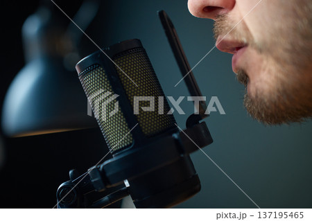 Close up man speaking into studio microphone with pop filter 137195465