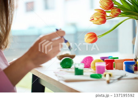 Woman painting Easter egg at home with pastel paints 137195592