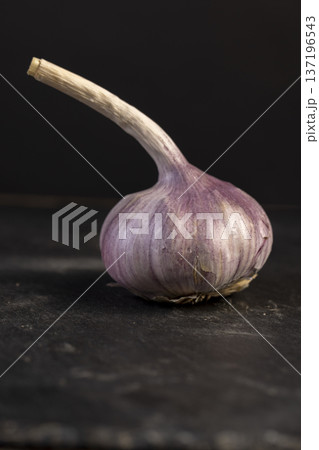 ripe purple garlic is scattered on a black table in the kitchen, garlic spices are on a black slate in the kitchen over cooking ripe purple garlic is scattered on a black table in the kitchen, garlic spices are on a black slate in the kitchen over cooking 137196543
