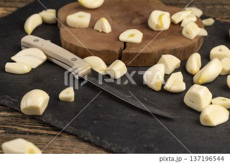 sliced garlic cloves scattered on black slate , peeled and sliced fragrant natural and fresh spices from garlic cloves scattered on black slate stone sliced garlic cloves scattered on black slate , peeled and sliced fragrant natural and fresh spices from garlic cloves scattered on black slate stone 137196544
