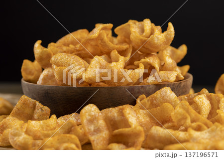 mashed potato chips fried in a large amount of sunflower oil, sprinkled with red hot pepper spices, crispy high-calorie chips with spices are scattered on the table 137196571