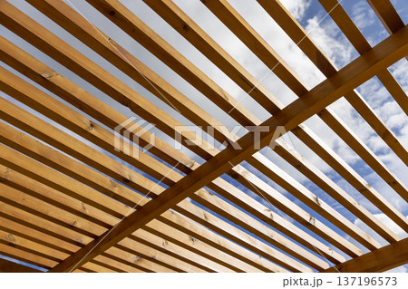 a wooden frame made of logs and planks in sunny weather against a blue sky with clouds, part of a wooden frame building under construction on the beach to create a good infrastructure a wooden frame made of logs and planks in sunny weather against a blue sky with clouds, part of a wooden frame building under construction on the beach to create a good infrastructure 137196573