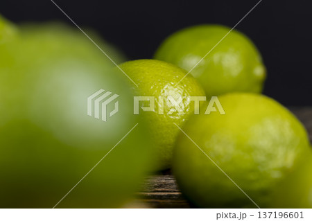 wet green ripe citrus limes scattered on the wooden table close up, ripe and juicy lime fruits for cooking, green limes covered with drops of water wet green ripe citrus limes scattered on the wooden table close up, ripe and juicy lime fruits for cooking, green limes covered with drops of water 137196601