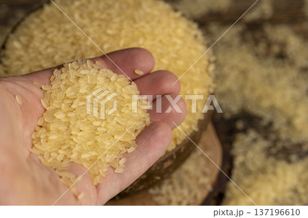 white ground dry hard rice, poured before cooking, poured natural pure polished rice on the table before cooking, The rice is poured into a bowl made from coconut shells 137196610