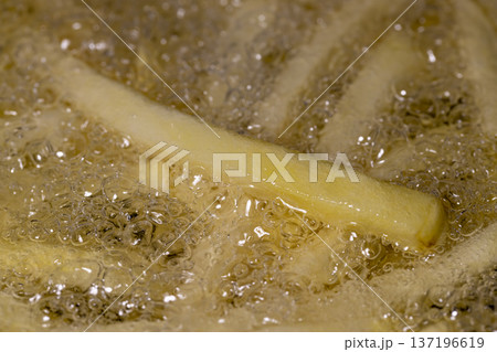 raw French fries in sunflower oil while frying in a frying pan, delicious fast food from frozen French fries in hot oil raw French fries in sunflower oil while frying in a frying pan, delicious fast food from frozen French fries in hot oil 137196619