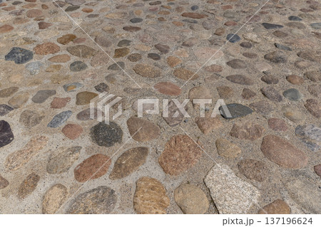a road made of stones of different sizes in rural areas, a reconstructed ancient road made of multicolored stones, cobblestones and pebbles 137196624