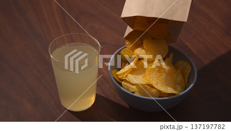 Man hand pour potato chips to blue bowl with ginger beer on background Man hand pour potato chips to blue bowl with ginger beer on background 137197782