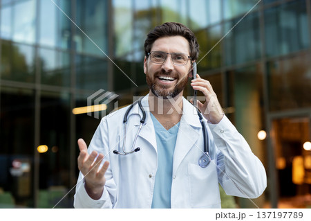 Confident male doctor laughing while on an important phone call outside a modern hospital, giving remote consultation and professional telehealth advice with stethoscope and glasses Confident male doctor laughing while on an important phone call outside a modern hospital, giving remote consultation and professional telehealth advice with stethoscope and glasses 137197789