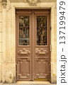 Ornate brown entrance door on a classic Haussmannian building facade in Paris, France, reflecting old European architecture 137199479