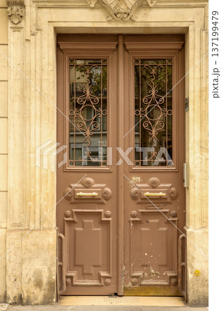 Ornate brown entrance door on a classic Haussmannian building facade in Paris, France, reflecting old European architecture 137199479