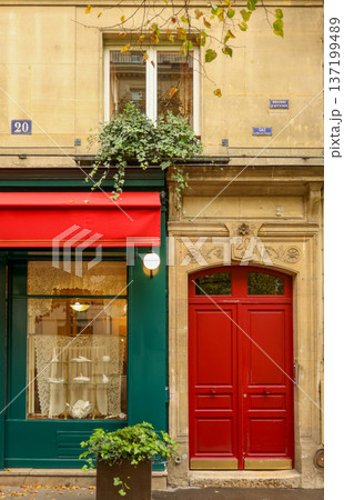 Paris urban architecture featuring vibrant red door, green storefront with awning, and detailed building facade 137199489