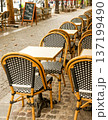 Paris outdoor cafe with empty bistro chairs and tables lining a cobblestone street, waiting for customers 137199490