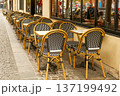 Parisian cafe terrace with iconic bistro chairs and empty tables lining a cobblestone sidewalk, ready for customers 137199492