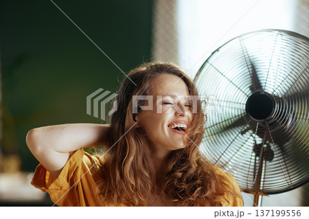 Carefree Woman Enjoying Fan\'s Cool Breeze Carefree Woman Enjoying Fan\'s Cool Breeze 137199556