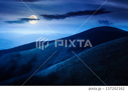 scenic mountain landscape in summer at night. beautiful travel background with rolling hills. lush green grassy hillside in full moon dappled light. narrow telephoto view. mysterious fantasy 137202162