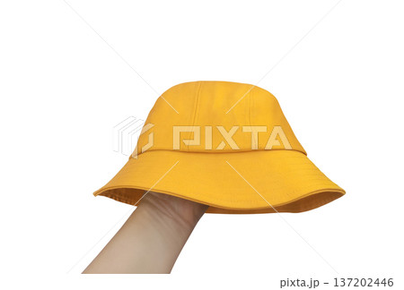 A yellow bucket hat is placed on a hand against a white background. 137202446