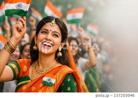 Happy woman in traditional saree waving Indian flag, celebrating Independence Day with crowd. 137203046