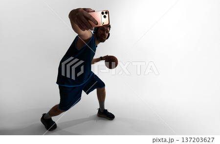 Basketball player taking selfie during training session wearing smartwatch and headphones 137203627