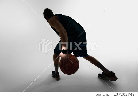 Basketball player dribbling ball wearing smartwatch in studio Basketball player dribbling ball wearing smartwatch in studio 137203748