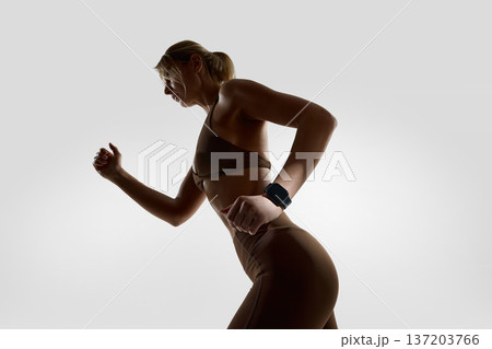 Woman in running pose wearing smartwatch in studio. Woman in running pose wearing smartwatch in studio. 137203766