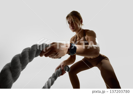 Close up of woman gripping battle ropes during training in studio with smartwatch Close up of woman gripping battle ropes during training in studio with smartwatch 137203780