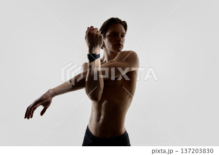 Athletic man stretching with smartwatch in modern studio. 137203830
