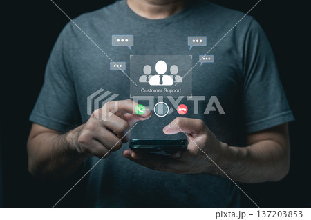 Man using smartphone with virtual customer support hologram and communication icons on dark background 137203853