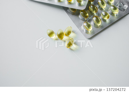 Omega 3 fish oil capsules in blisters on white table close up. Vitamins and supplements, healthcare and medicine. Omega 3 fish oil capsules in blisters on white table close up. Vitamins and supplements, healthcare and medicine. 137204272