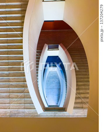 Symmetrical modern spiral staircase viewed from above with curved rails and marble steps 137204279