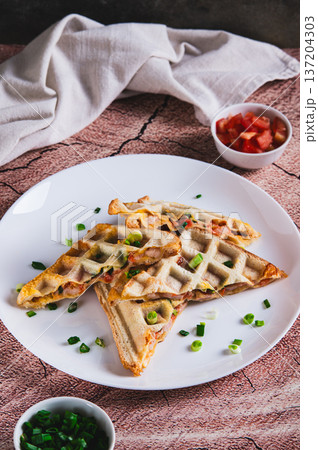 Bacon, cheese and tomatoes baked in waffle bread on a plate on the table vertical view Bacon, cheese and tomatoes baked in waffle bread on a plate on the table vertical view 137204303
