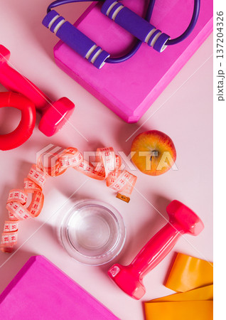 A glass of water and an apple for a diet and sports equipment on the table top and vertical view A glass of water and an apple for a diet and sports equipment on the table top and vertical view 137204326