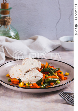Boiled chicken fillet and mixed vegetables on a plate on the table vertical view 137204331