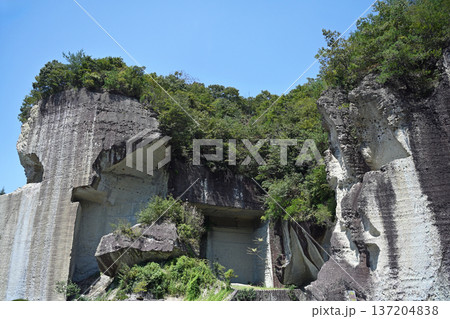 青空にそびえ立つ剥き出しの巨大な大谷石岩壁 137204838