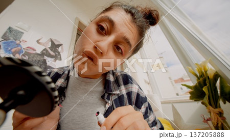 Serene lady meticulously improves her look in calm surroundings Serene lady meticulously improves her look in calm surroundings 137205888