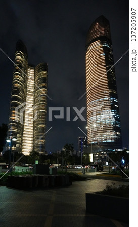 Modern skyscrapers illuminated at night in urban cityscape Modern skyscrapers illuminated at night in urban cityscape 137205907