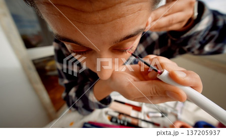 Performer carefully applying bold eyeliner in backstage setting 137205937