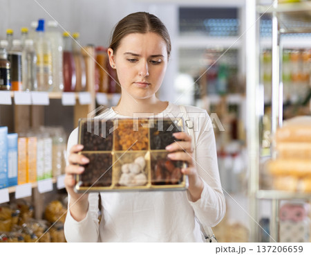 Young woman chooses dried fruits at grocery store 137206659
