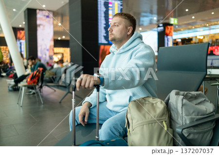 Male traveler waiting at airport terminal with luggage 137207037