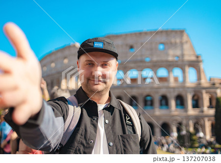 Handsome 30s tourist visiting Colosseum in Rome, Italy. Young man taking photo in front of famous Italian landmark  137207038